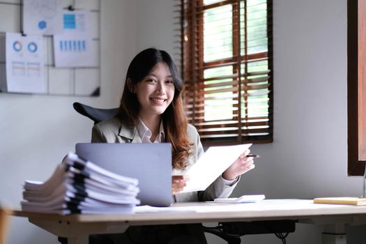 Charming Asian woman working at the office using a laptop Looking at the camera..