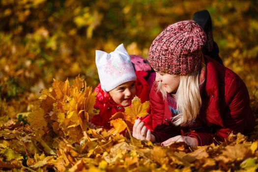 Young mother with her little daughter in an autumn park.
