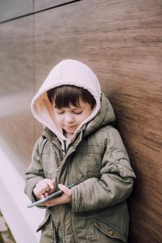 A boy looks at his phone in the city of lifestyle . Modern technologies. Modern children. A child and a phone. Urban lifestyle