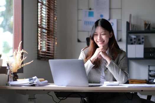 Beautiful young asian woman sitting at coffee shop using laptop. Happy young businesswoman sitting at table in cafe with tab top computer..