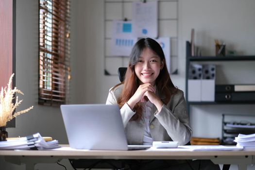 business Asian woman working online at home office and looking at the camera..