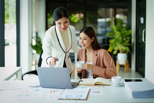 A portrait of two female employees using computers while working to analyze their finances and increase their marketing strategies to combat their competitors.