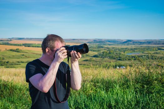 Photographer takes aim and takes pictures of nature outdoors while in the field in summer