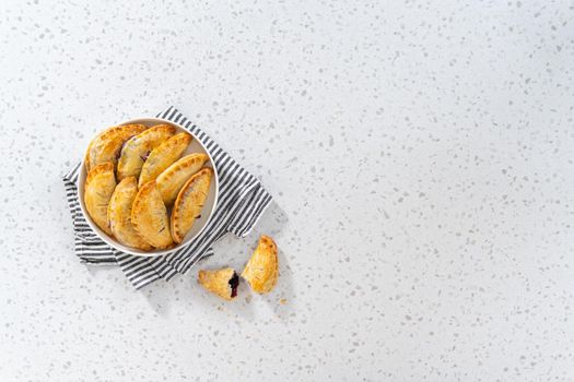 Flat lay. Freshly baked sweet empanadas with blueberries on the kitchen counter.