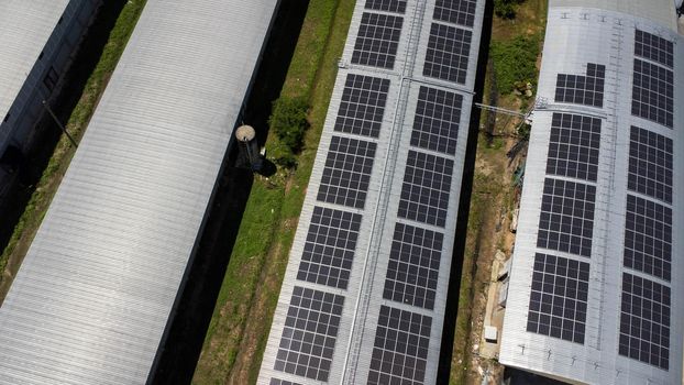 Aerial view of Solar panels installed on a roof of a large industrial building or a warehouse. Top view of solar power station with factory. sustainable energy concept.
