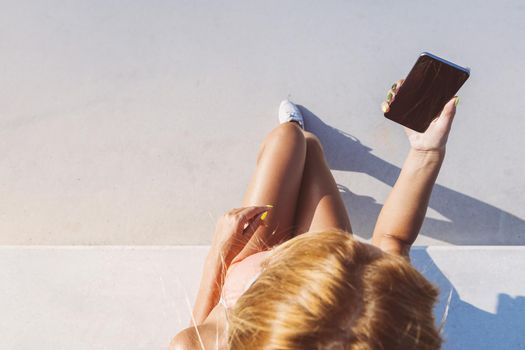 attractive female athlete looking at the phone before running, sports girl consulting the sport app of her mobile after training and run, technology for fitness and healthy lifestyle concept, top view