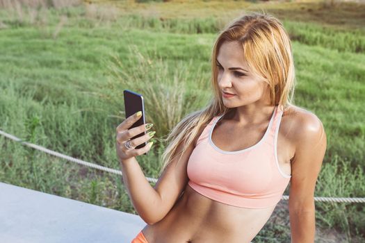 attractive female athlete looking at the phone before training, athletic sporty woman consulting the sport app on a break, technology fitness and healthy lifestyle concept, copy space for text