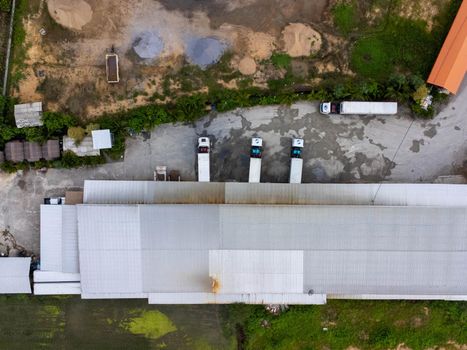 Aerial view of goods warehouse with trucks loading at logistic center. Logistics center in industrial city zone from above. Logistic and transport concept