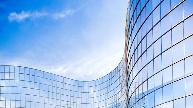 Glass buildings business concept. The glass facade of a skyscraper with a mirror reflection of sky windows. Bright sunny day with sunbeams in the blue sky. Modern buildings background. 3d Rendering