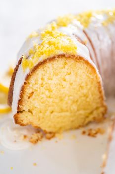 Sliced lemon bundt cake decorated with lemon zest on a cake stand.