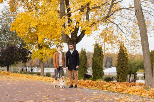 Father and son with a pet on a walk in the autumn park.