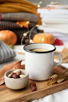 Hello fall. Cozy warm image. Cozy autumn composition, sweater weather. Hot tea with lemon and nuts on wooden tray surrounded with autumn leaves and sweaters, mug mockup design