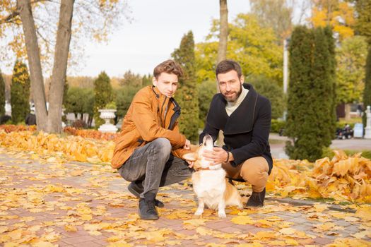 Father and son with a pet on a walk in the autumn park.