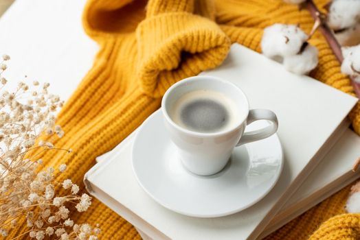 cozy composition of warm yellow sweater, white books , cup of hot coffee and dry flowers , top view flat lay
