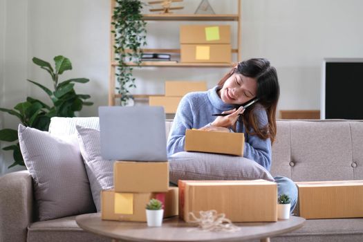 Startup small business SME, Entrepreneur owner using smartphone or tablet taking receive and checking online purchase shopping order to preparing pack product box. Selling online ideas concept.