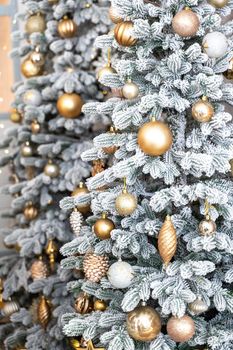 Close-up of a festively decorated outdoor Christmas tree with balls on a blurred sparkling fairy background. Defocused garland lights, bokeh effect