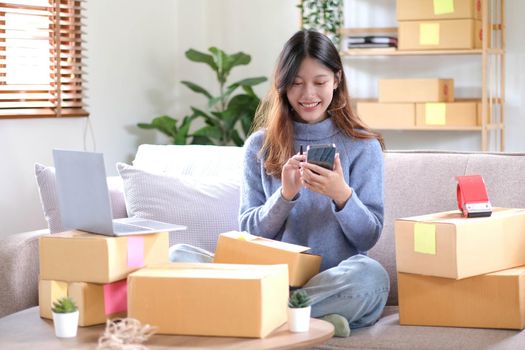 Portrait of a Small Business Startup, SME Owner, Female Entrepreneur work on parcel boxes Receipts and check orders online to prepare boxes. Selling to customers. Online SME business idea..
