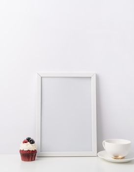 Art photo frame mockup with cup of coffee and cupcake, white background template