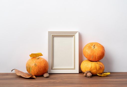 Photo frame and white pumpkins. Mockup Copy space for artwork. Autumn decor in interior.