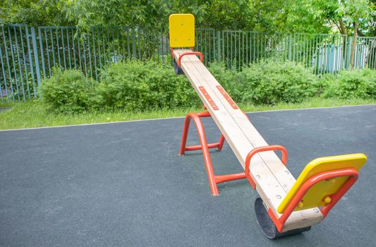 Balancing swing in the form of a wooden board on an empty outdoor playground, children's play area.