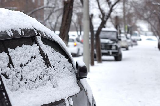 Passenger car with snowflakes at snowy overcast weather, side door with snow close up, urban landscape at cold snowfall season