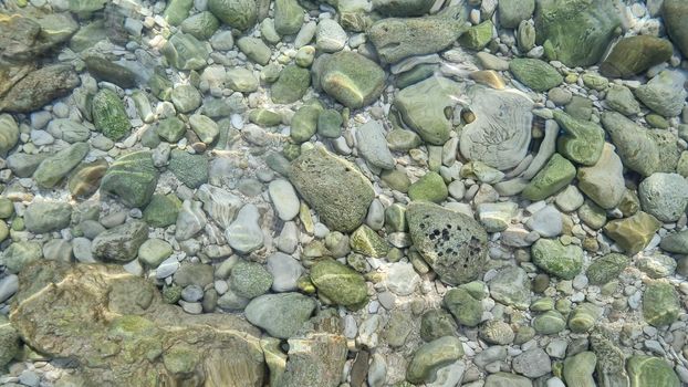 Blurred abstract marine background, stones underwater. Clear sea water covers the rocks.