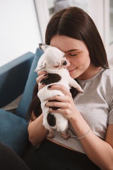 Vertical close up of a happy woman cuddling with adorable chihuahua puppy