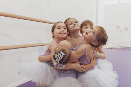 Adorable little girls hugging each other, enjoying dancing at ballet school. Cute little ballerinas embracing, having fun after ballet class, copy space. Diversity, support, togetherness concept