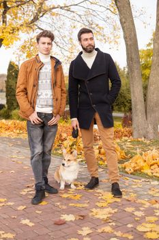 Father and son with a pet on a walk in the autumn park.