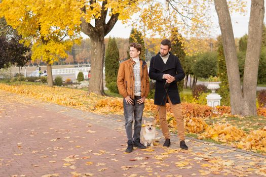 Father and son with a pet on a walk in the autumn park.