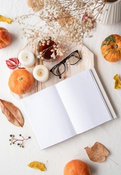 Back to school. Cozy autumn. white blank book with autumn leaves, glasses and candles on white table , mockup design