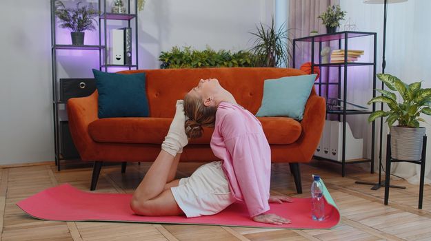 Girl doing yoga stretching excersices on mat, workout, burning fat calories, training strength, practicing effort domestic fitness females aerobics. Sport motivation. Young woman at home apartment