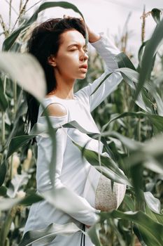 A brunette girl in a white dress in a cornfield. The concept of harvesting.