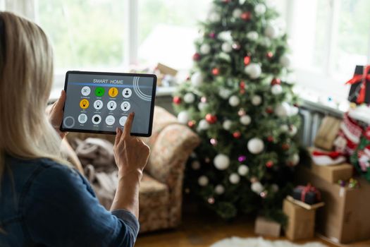 Hand holding a tablet with smart home system applications, digital tablet in christmas day.