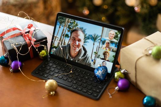 Christmas video call with happy family. Concept of families in quarantine during Christmas because of the coronavirus. Xmas still life with a tablet in a cozy room.