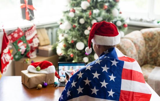 man are celebrating New Year, sitting, chatting and smiling near tablet in Santa's hats