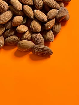 Peeled almond nuts on orange background