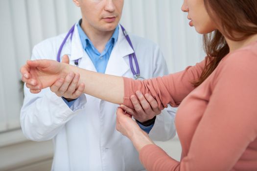 Cropped shot of a woman showing her injured arm to the doctor