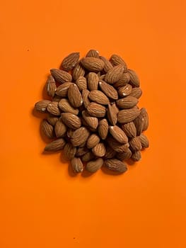 Peeled almond nuts on orange background