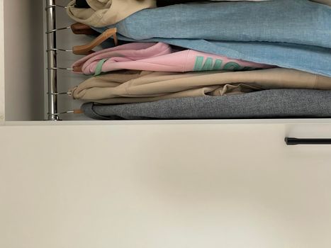 Cropped vertical shot of clothes on hangers in the wardrobe