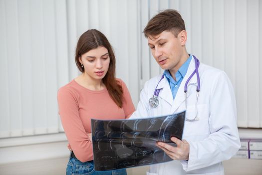 Mture male doctor talking to his female patient, explaining her MRI scanning results