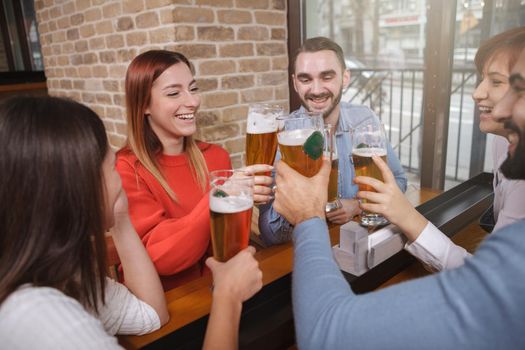 Diverse group of young people enjoying drinking beer together at the pub. Friendship, weekend, relax concept