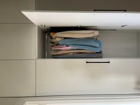 Vertical shot of a wardrobe with open door and clothes hanging inside