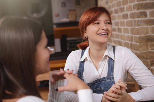 Young happy woman laughing, enjoying talking to her friend at the cafe. Women, happiness concept