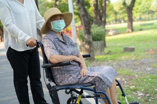 Help Asian senior or elderly old lady woman on wheelchair and wearing a face mask for protect safety infection Covid19 Coronavirus in park.