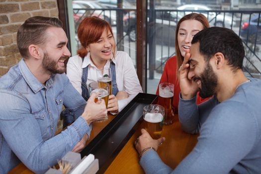 Group of young people having fun together, drinking beer at the pub