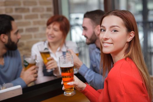 Close up of a happy beautiful woman enjoying her beer at the pub with friends, copy space