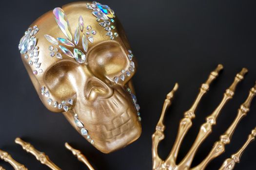 On a black background, a golden skeleton skull decorated with rhinestones . High quality photo