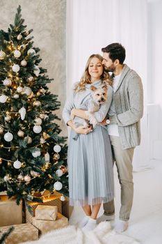 Happy family: mom, dad and pet. Family in a bright New Year's interior with a Christmas tree.