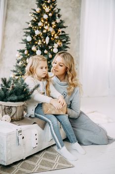 Happy family: mother and daughter. Family in a bright New Year's interior with a Christmas tree.